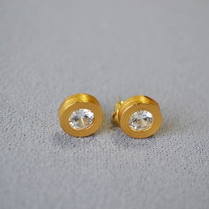 Macro shot of gold brushed texture earrings featuring a sparkling inset zircon stone