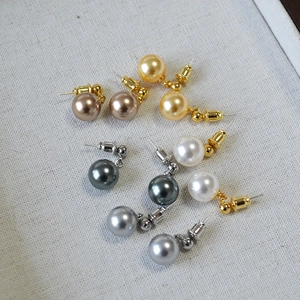 Detailed view of multi-color pearl earrings set with gold and silver studs on white fabric