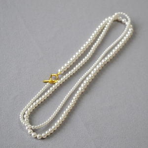 French style layered white pearl necklace with gold OT clasp on a minimalist grey background