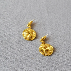 Macro detail of gold-plated brass earrings with a unique spiral concentric texture design