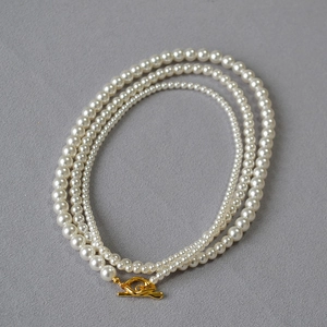 Detailed macro view of triple-layered pearl necklace with golden irregular OT metal clasp