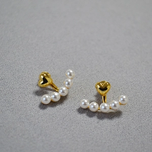 Close-up of elegant gold heart earrings featuring five lustrous curved white pearls