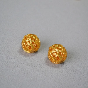 Macro detail of gold woven ball stud earrings with intricate twisted metal wire texture