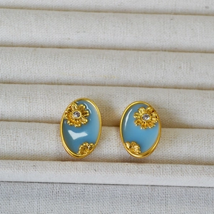 Macro view of vintage oval enamel earrings with gold sunflower and zircon inlay