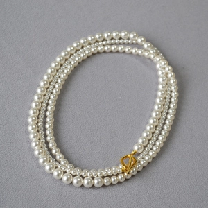 Detailed view of layered cream pearls with a golden toggle clasp on a stylish necklace