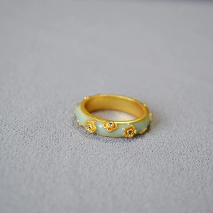 Detail of vintage brass gold ring with green enamel and small zircon floral patterns
