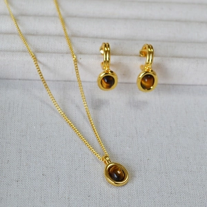 Vintage gold necklace and tiger eye stone earring set on white textured fabric