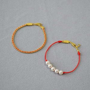 French retro handmade red rope bracelet with pearls and gold beads on gray fabric