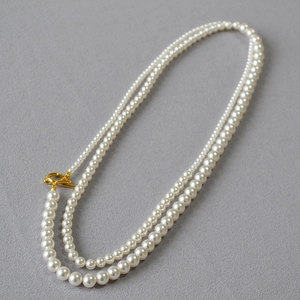 Detail of elegant pearl necklace featuring various bead sizes and a gold toggle clasp