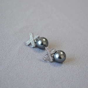Detail of X-shaped silver earrings with micro-paved zircons and grey pearl drop