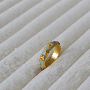Detail of vintage gold-plated ring with light green enamel and floral zircon accents