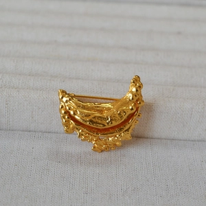 Macro shot of gold-plated brass brooch showing irregular lava texture and back pin detail