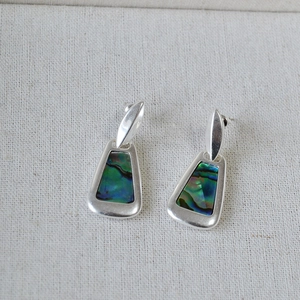 Macro detail of geometric silver earrings with iridescent colorful abalone shell inlays