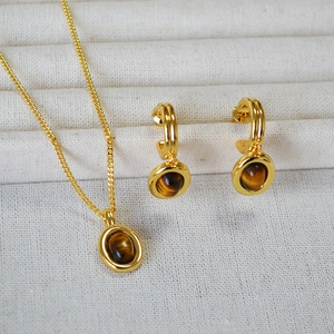Detailed view of tiger's eye necklace and C-shaped earrings on jewelry display tray