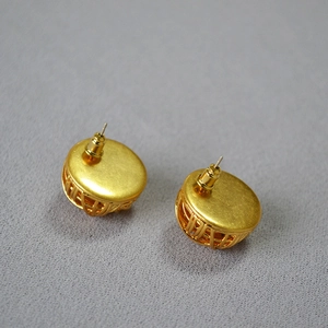 Close-up of golden hollow sphere earrings with 3D woven texture and stud detail