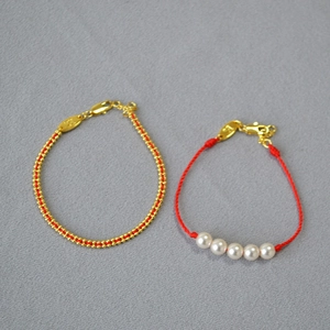 Detail view of handmade red string bracelets with gold beads and white pearls set