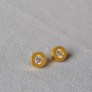 Macro shot of minimalist gold round stud earrings with brilliant-cut cubic zirconia