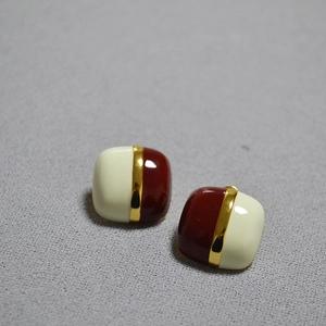 Detail of square vintage enamel earrings with cream and brown contrast colors