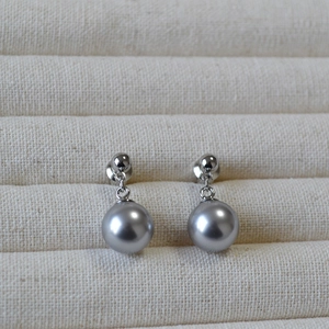 Macro detail of minimalist S925 silver stud earrings with lustrous dark grey pearls
