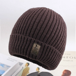 Close-up of dark brown ribbed knit beanie with leather patch on vintage books