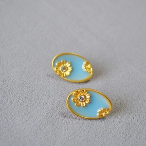 Close-up of vintage oval enamel earrings with gold daisy flowers and crystal accents