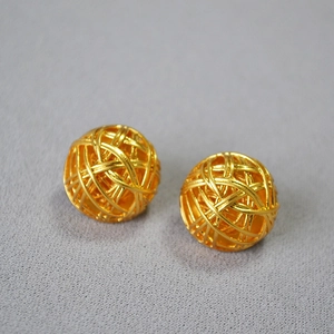Macro detail of gold-plated hollow woven yarn ball earrings with 925 silver needles