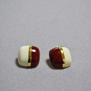 Detail of square geometric stud earrings with cream and burgundy enamel finish