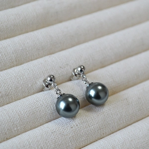 Close-up of elegant dark grey pearl earrings with silver 925 needles on jewelry tray