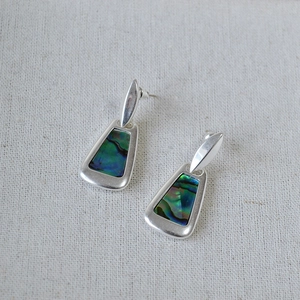 Detail view of geometric silver earrings with iridescent colorful abalone shell inlay