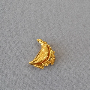 Macro detail of irregular crescent gold brooch with artistic lava textured finish