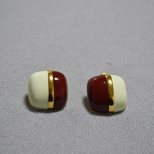 Macro view of geometric square enamel earrings with cream and dark red color-blocking