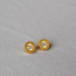 Detailed view of gold plated round stud earrings with sparkling cubic zirconia inlay