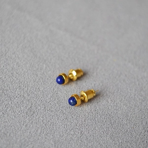 Detail von runden Lapis-Lazuli-Steinen in minimalistischen vergoldeten Ohrsteckern