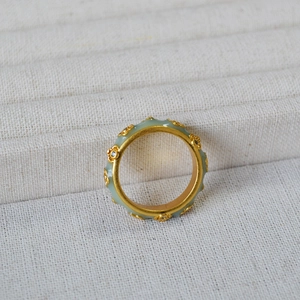 Macro view of gold-plated flower ring with green enamel finish and crystal details