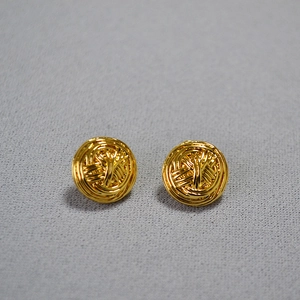 Detail of gold knot earrings featuring a woven metal wire design on gray fabric