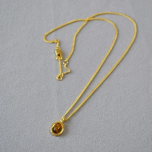 Detailed view of a gold-toned necklace featuring an oval tiger eye gemstone pendant