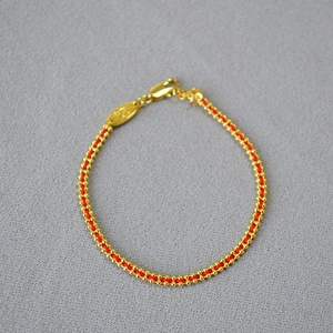 Detail of red rope bracelet with pure gold beads and lobster clasp closure