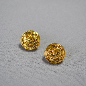 Detail of French vintage gold woven knot stud earrings on a textured background