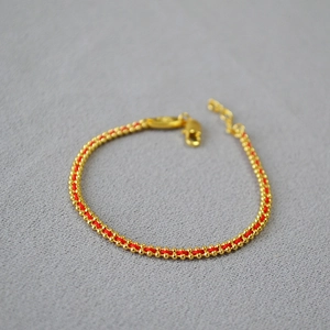 Detail of red woven bracelet with golden beads and adjustable lobster clasp closure