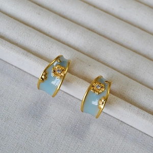 Detail of vintage French blue enamel C-shape hoop earrings with golden daisy zircon