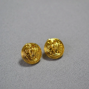 Detailed view of gold woven metal sphere earrings with vintage textured hollow design