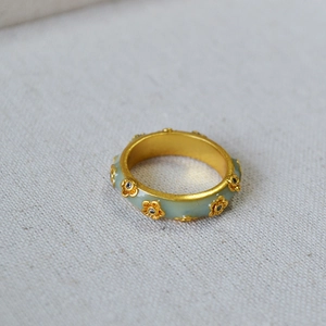 Macro shot of French vintage gold flower ring with green enamel and black zircon on linen