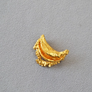Detail showing irregular gold lava texture and organic molten design of the metal brooch