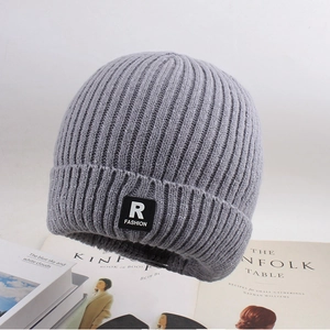 Detail of dark grey ribbed knit beanie showing thick texture and FASHION logo patch