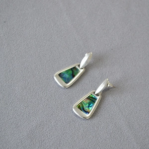 Detailed view of geometric trapezoid earrings with colorful abalone shell inlay inserts