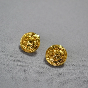 Close-up of golden woven wire ball stud earrings with intricate hollow craft design