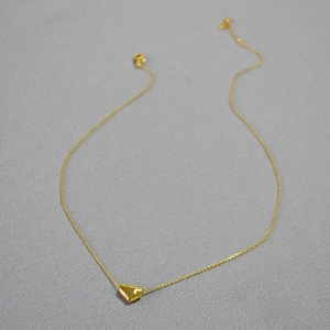 Détail d'un collier pendentif cœur doré poli avec une finition miroir lisse et élégante