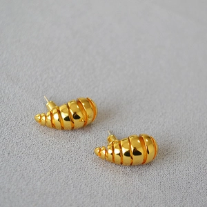 Gros plan détaillé de boucles d'oreilles spirales dorées avec texture élégante de coquillage