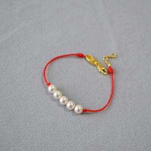Detail of red woven thread bracelet with five lustrous white pearls and gold clasp
