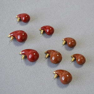 Macro detail of red and mocha brown enamel teardrop earrings with gold plating